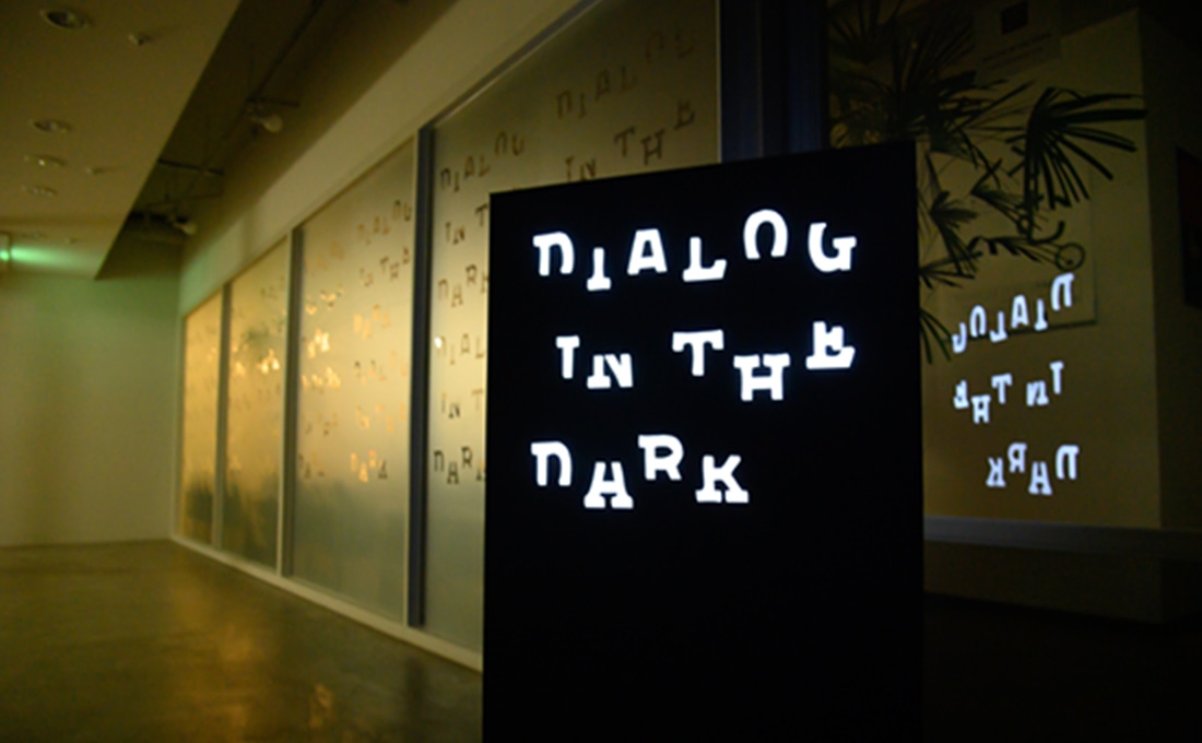 薄暗い廊下の角に設置されたダイアログ・イン・ザ・ダークのロゴ